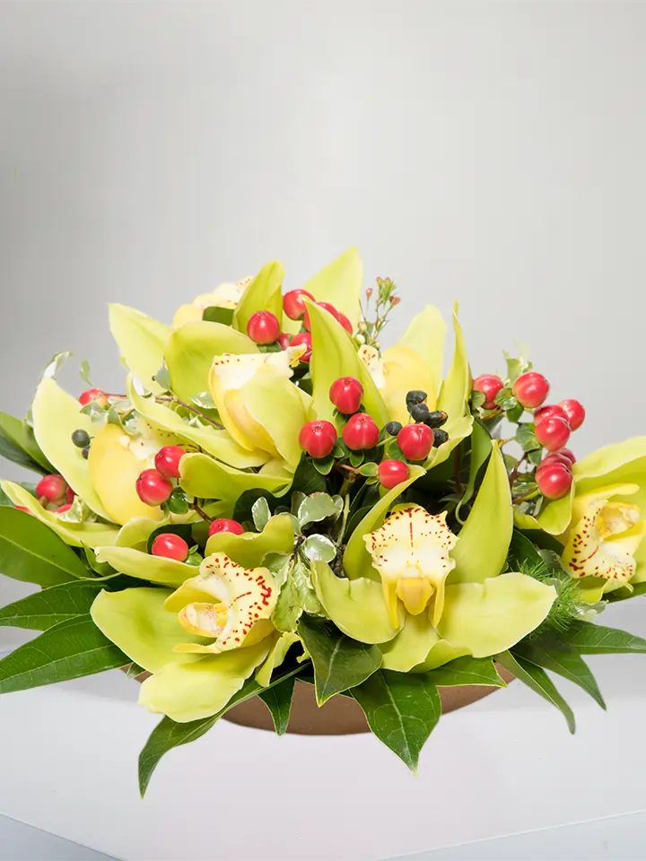Centrotavola di fiori di cymbidium gialli e bacche rosse close up
